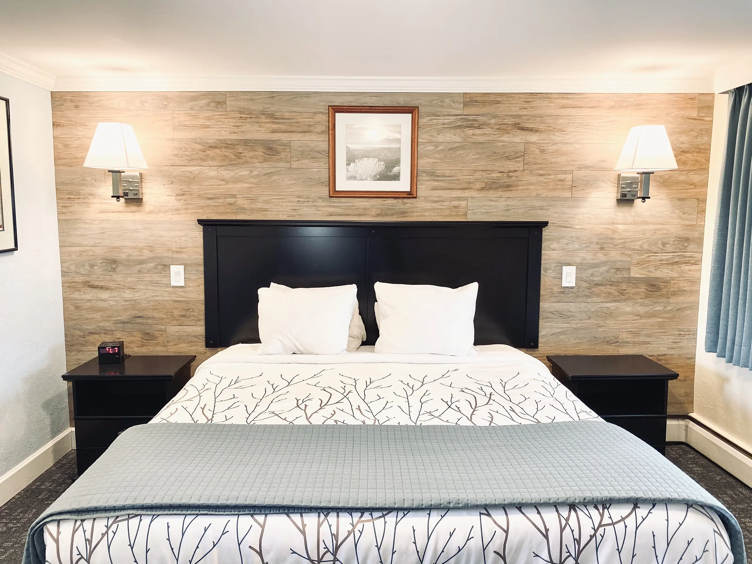 Standard King Bed in a hotel room with wood paneled accent wall