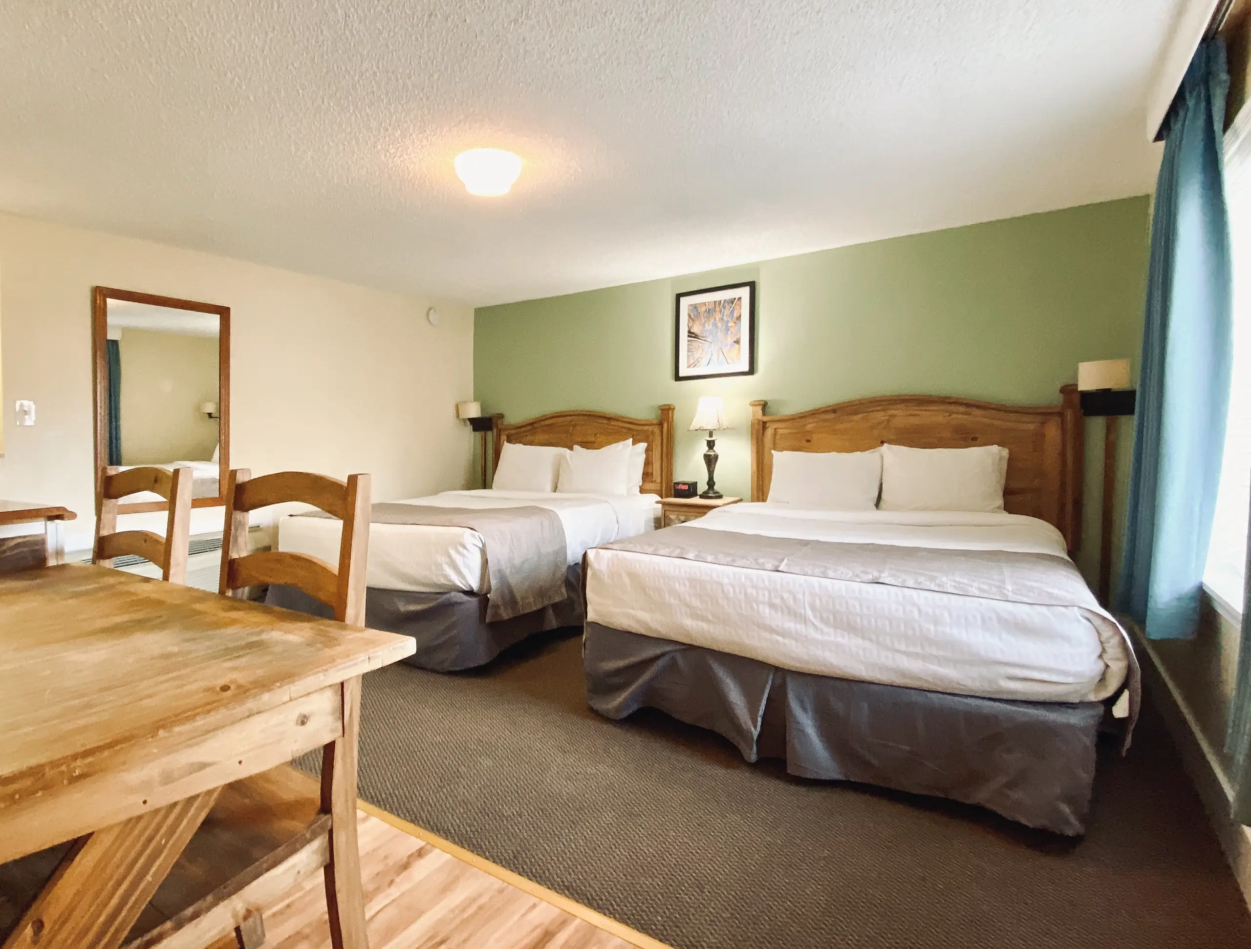 Two beds in a hotel room with a wooden table