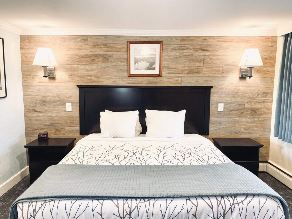 Standard King Bed in a hotel room with wood paneled accent wall