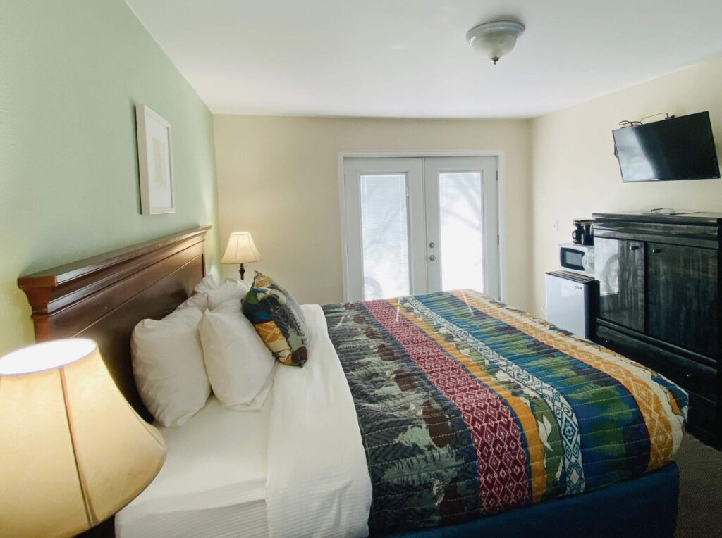 King bed with patterned quilt and tv on wall